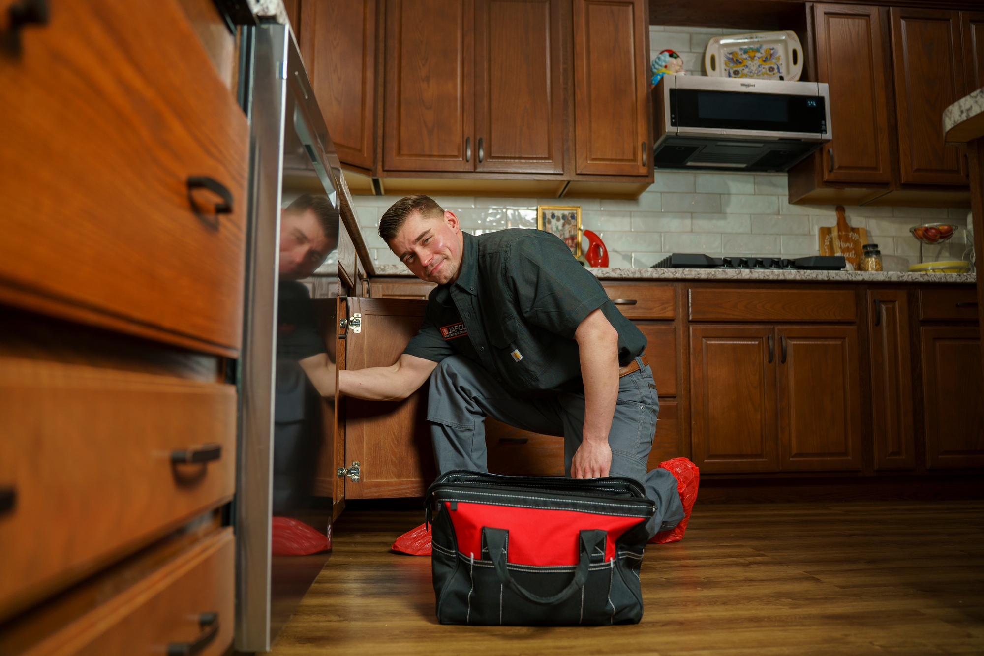 plumber working underneath kitchen plumbing
